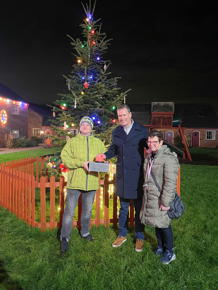 Gareth Griffiths attending the Save the Family Christmas light switch on, standing in front of the tree with 2 attendees